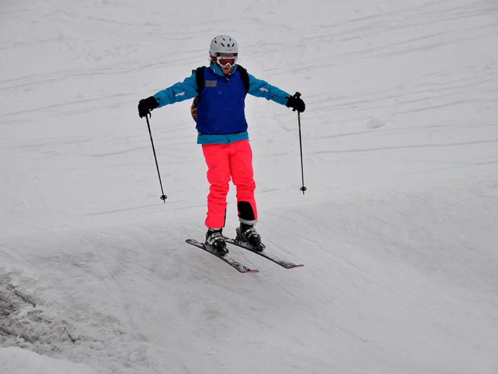 Skifahrerin in oranger Hose zieht einen Schwung.